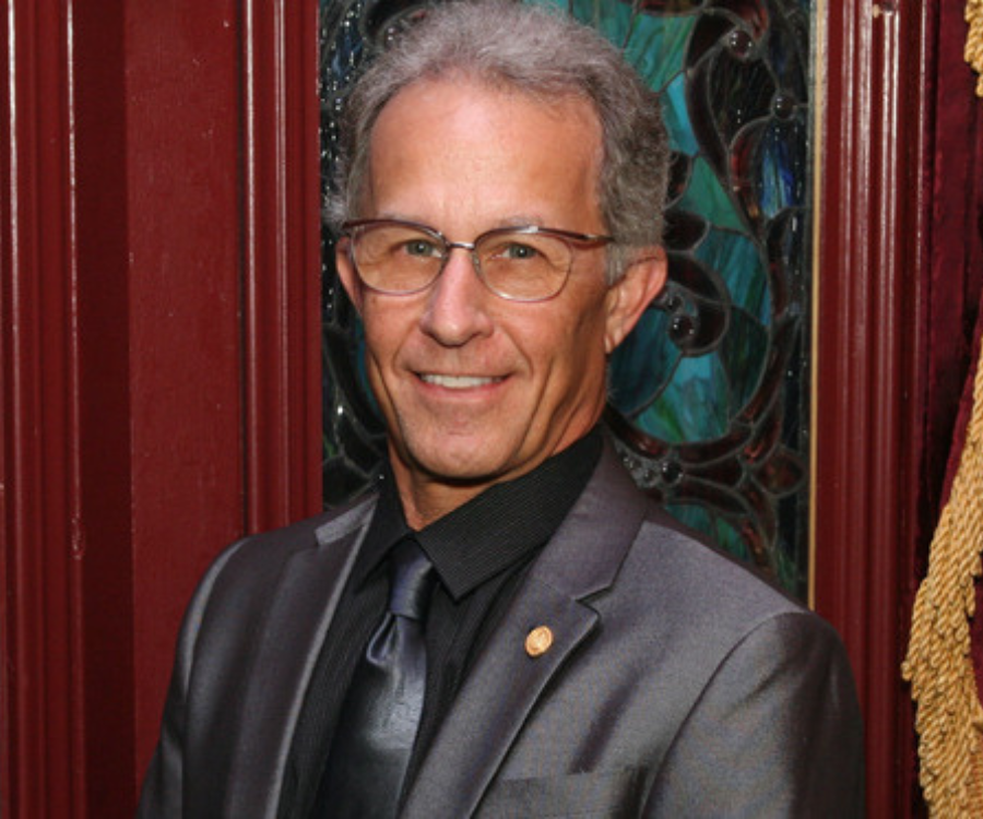 Image of gentleman with gray hair wearing a silver suit.